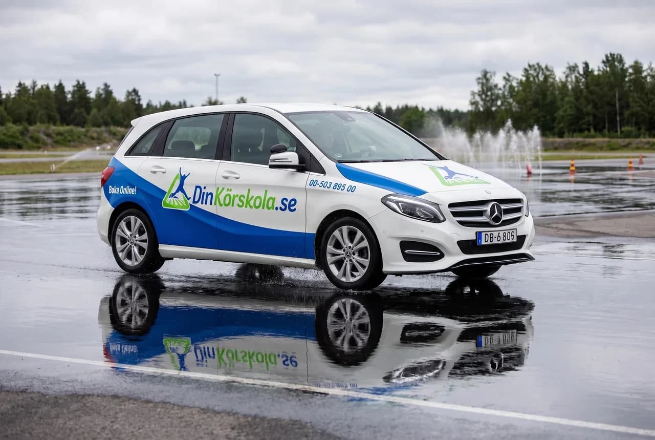 Din Körskolas egen bil på halkbanan, med vatten som sprutar kring hjulen