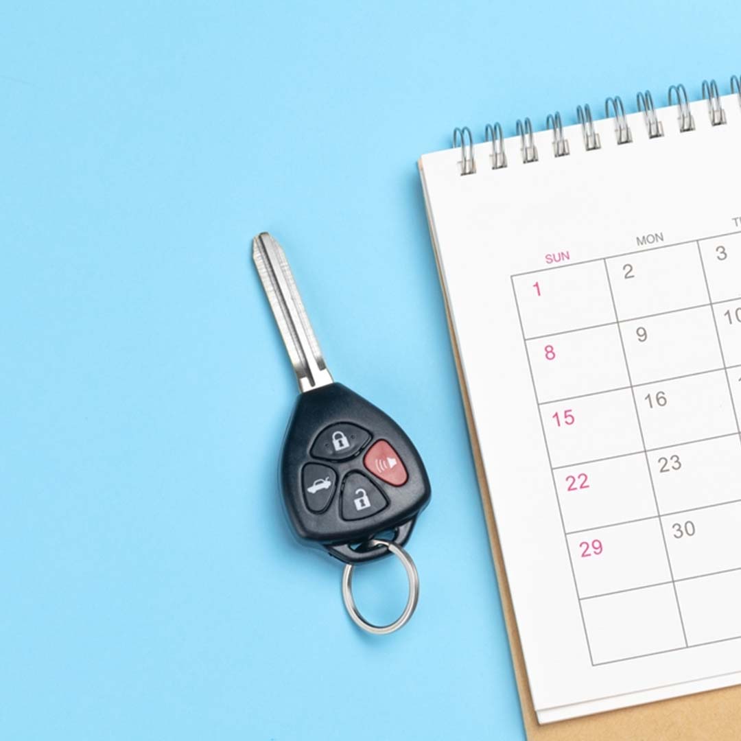 Car key on a desk calendar with marked dates Car key on a desk calendar with marked dates